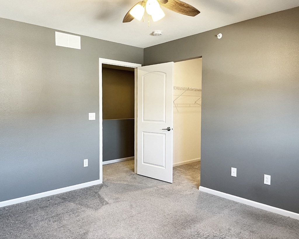 A room with a white door and a ceiling fan.