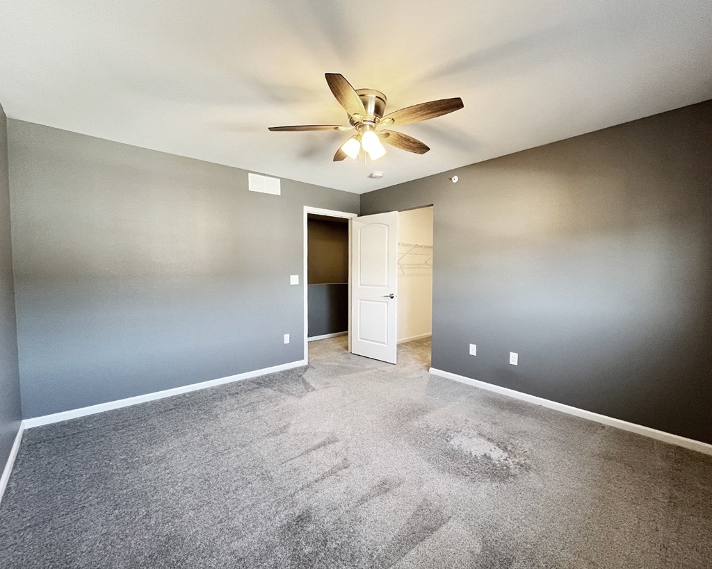 A room with a ceiling fan and a door.