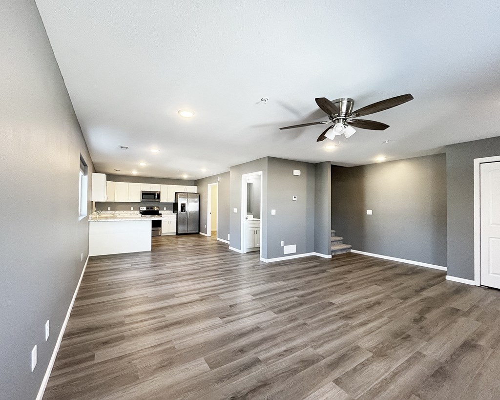 A spacious room with a ceiling fan and wooden flooring.