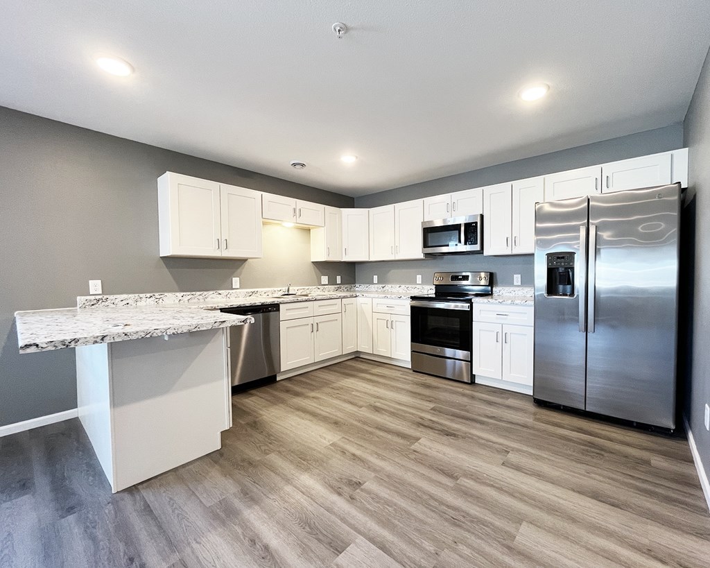 A kitchen with a marble countertop and stainless steel appliances.
