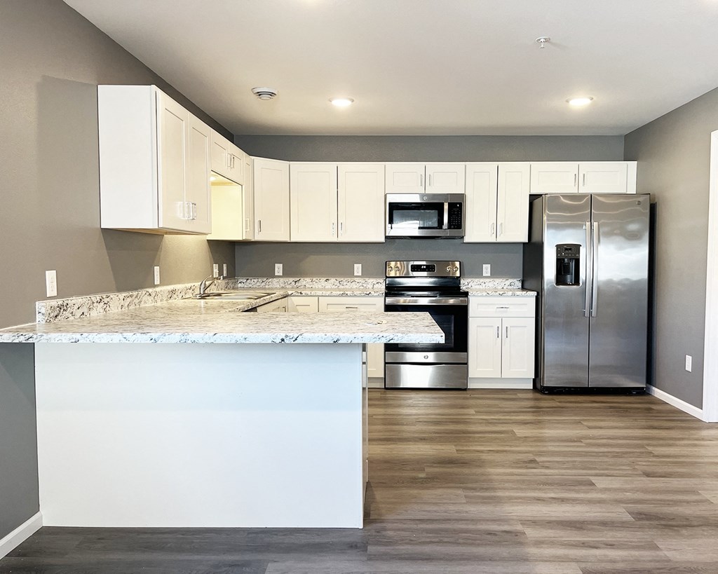 A kitchen with a marble countertop and stainless steel appliances.