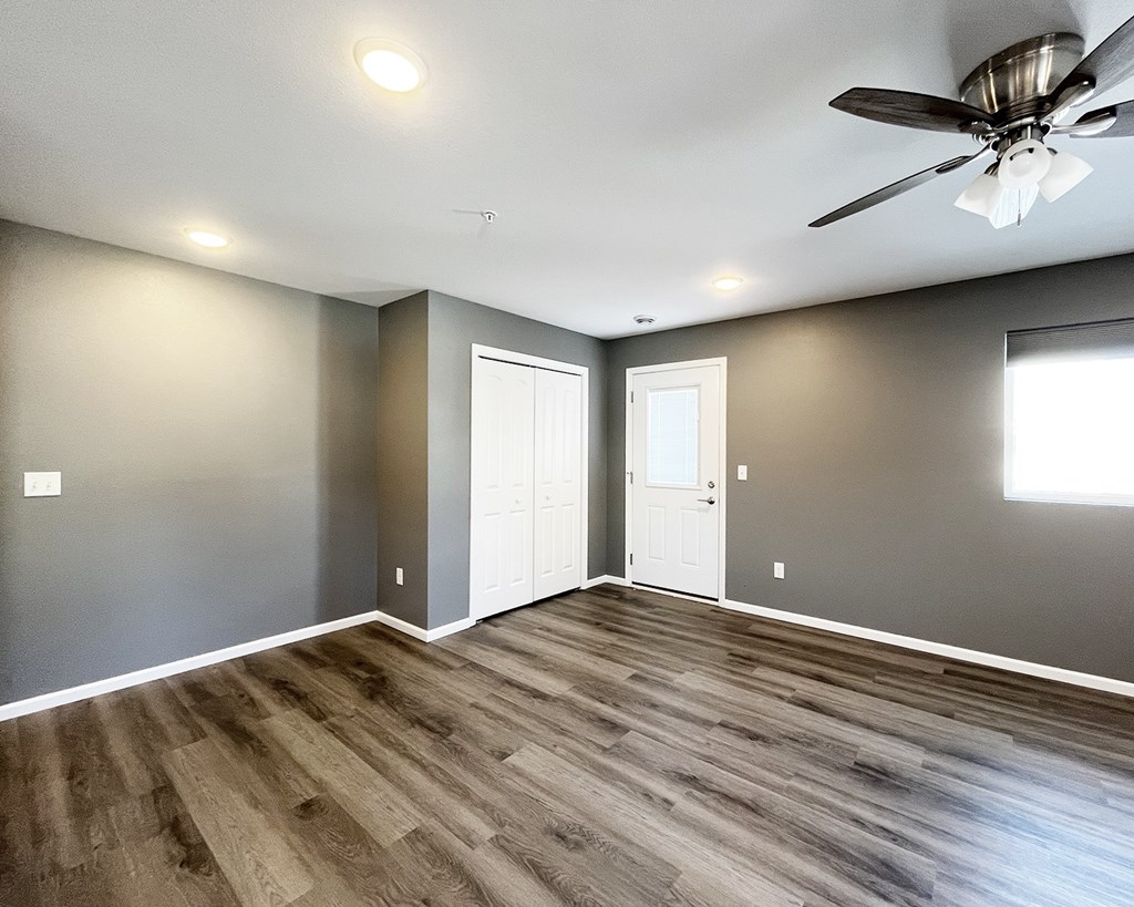 A room with a ceiling fan and wooden flooring.