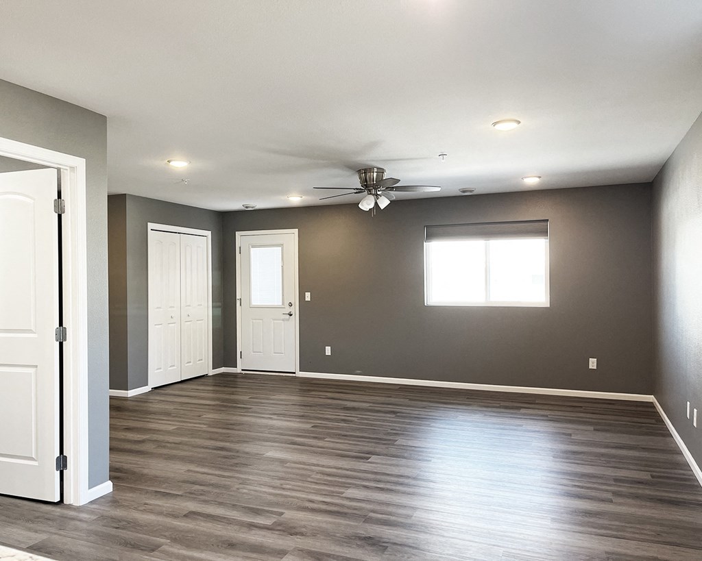 A room with a ceiling fan and wooden flooring.