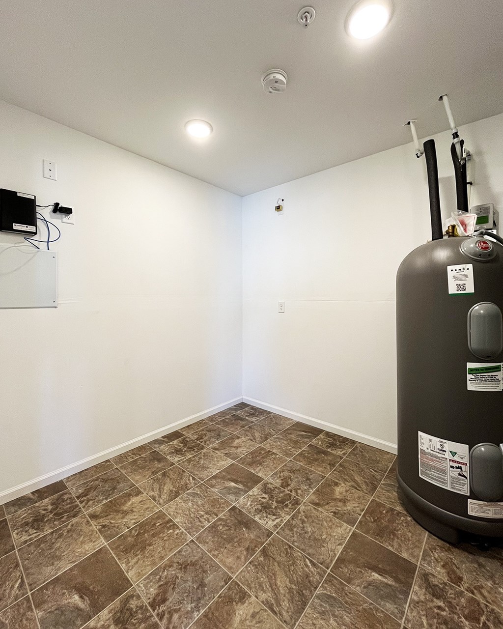 A room with a tiled floor and a water heater.