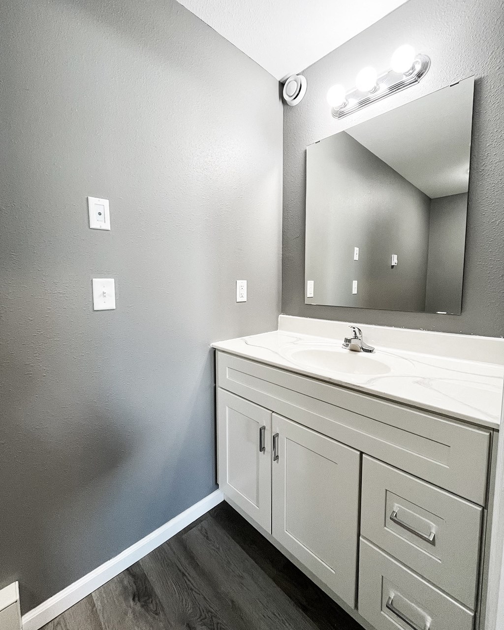 A bathroom with a white sink and a mirror above it.