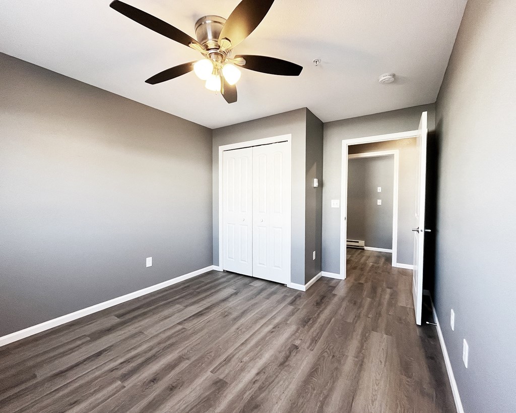 A room with a ceiling fan and wood flooring.