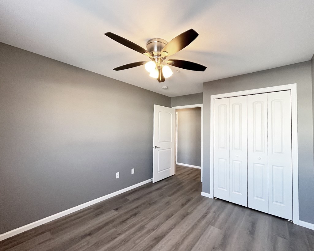 A room with a ceiling fan and wood flooring.