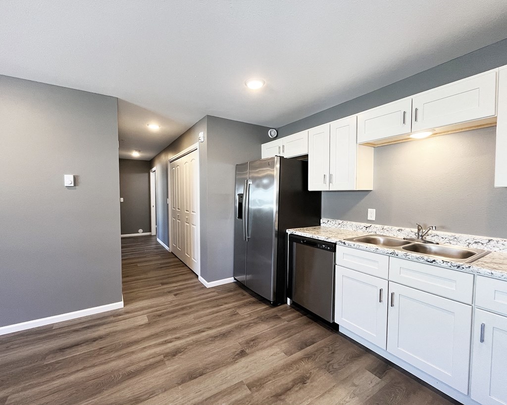 A kitchen with white cabinets and a stainless steel refrigerator.