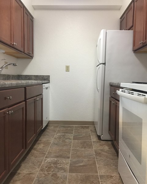A kitchen with brown cabinets and a white refrigerator.