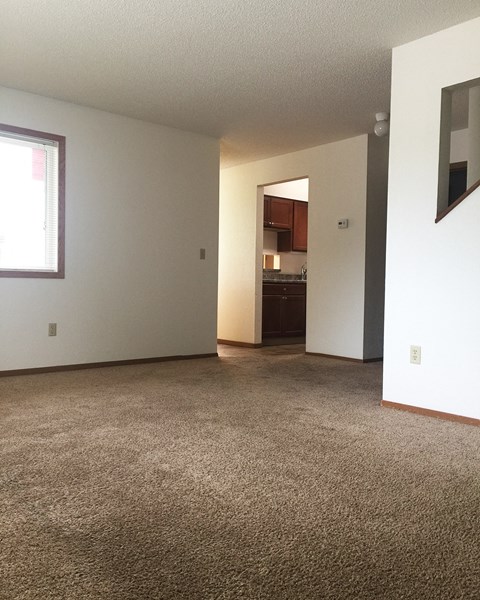 A room with a carpeted floor and a doorway leading to another room.