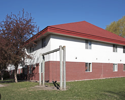 A white and red building with a red roof and a tree in front.