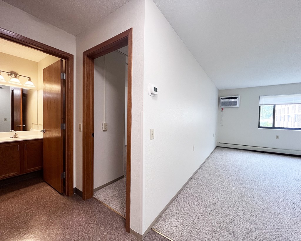 A large, empty room with a carpeted floor and a window.