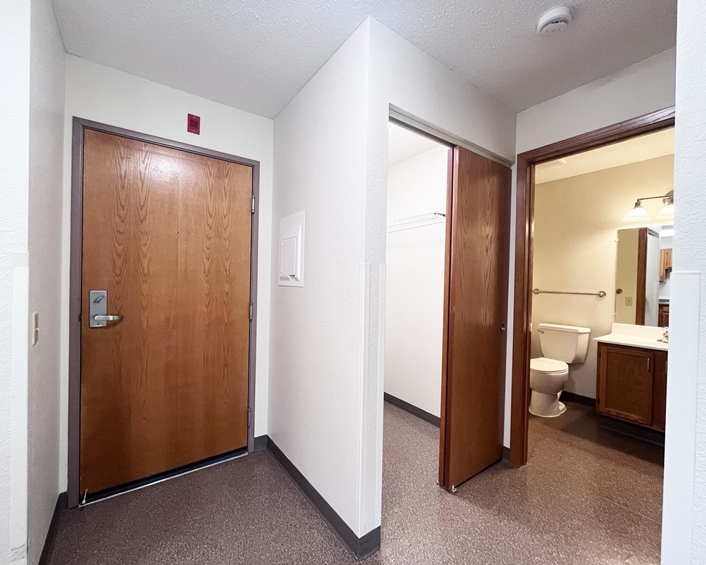 A bathroom with a toilet, sink and mirror.