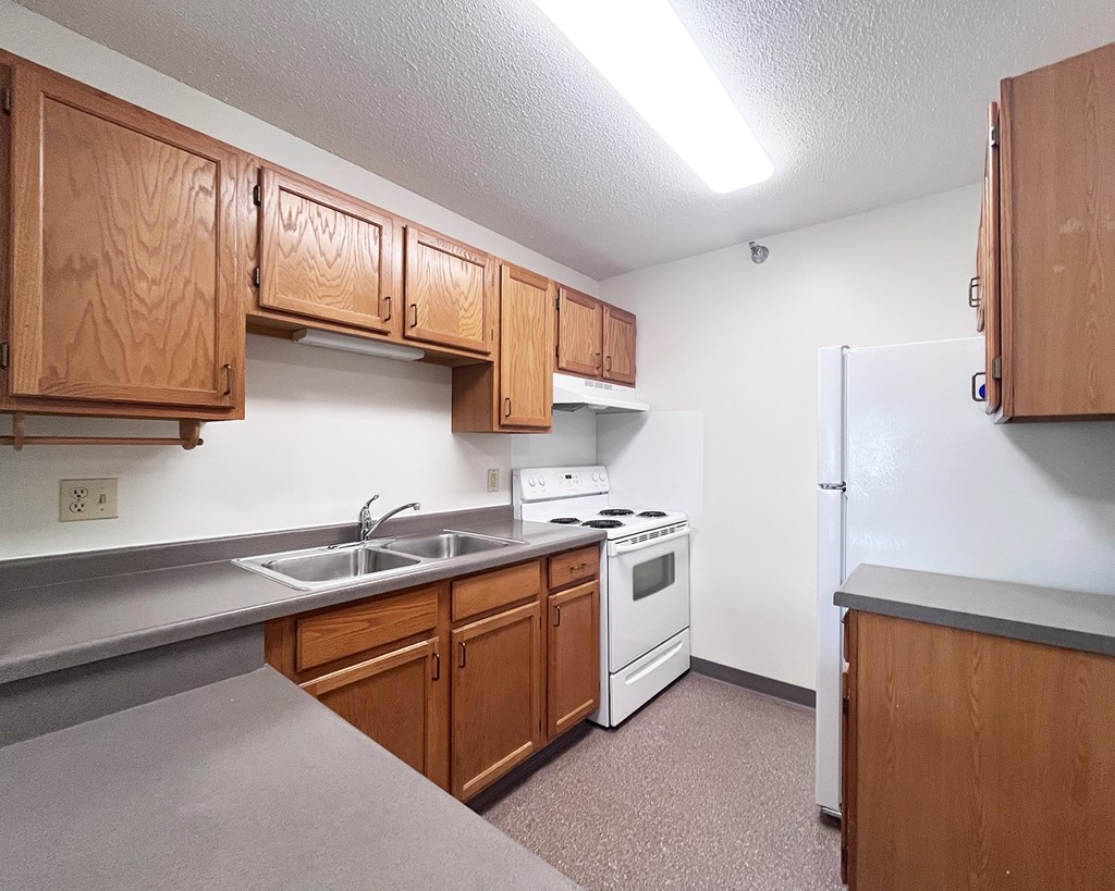 A kitchen with wooden cabinets and a white stove top oven.