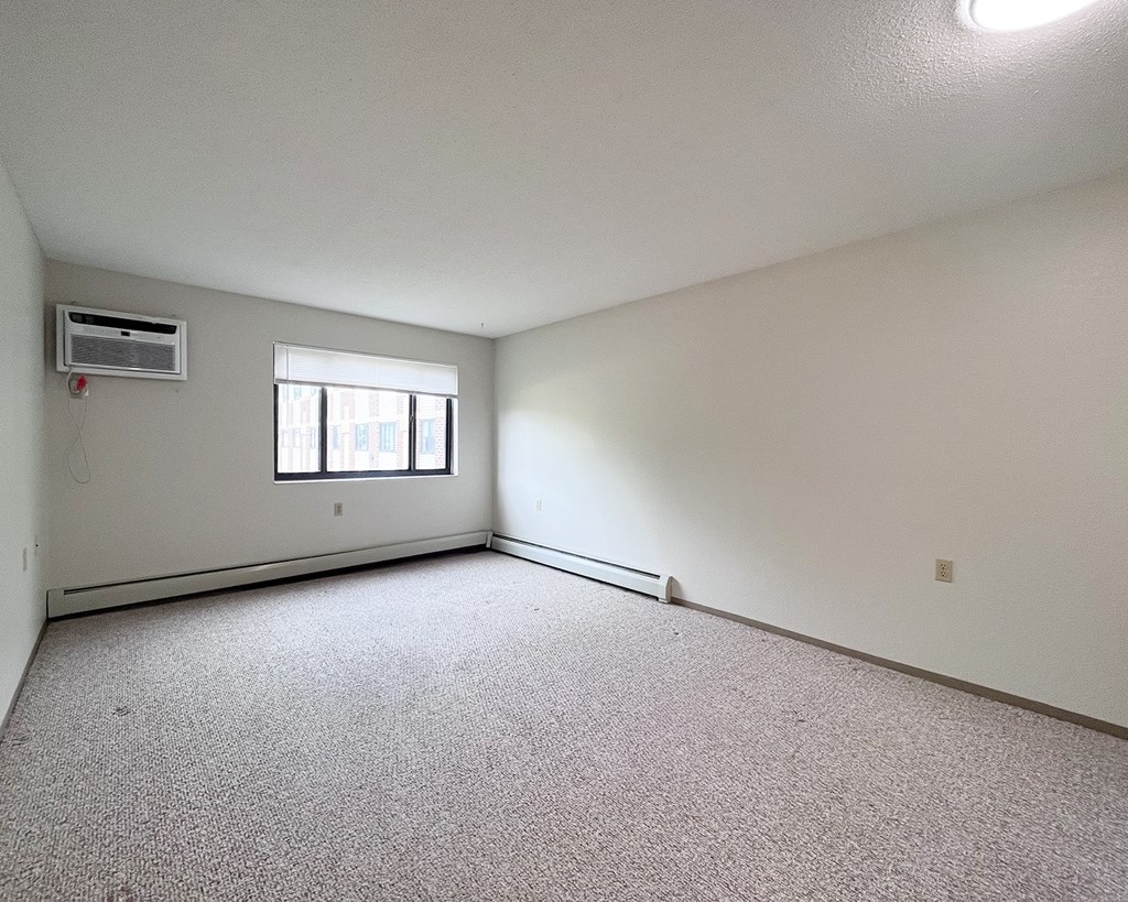 A room with a window and carpeted floor.