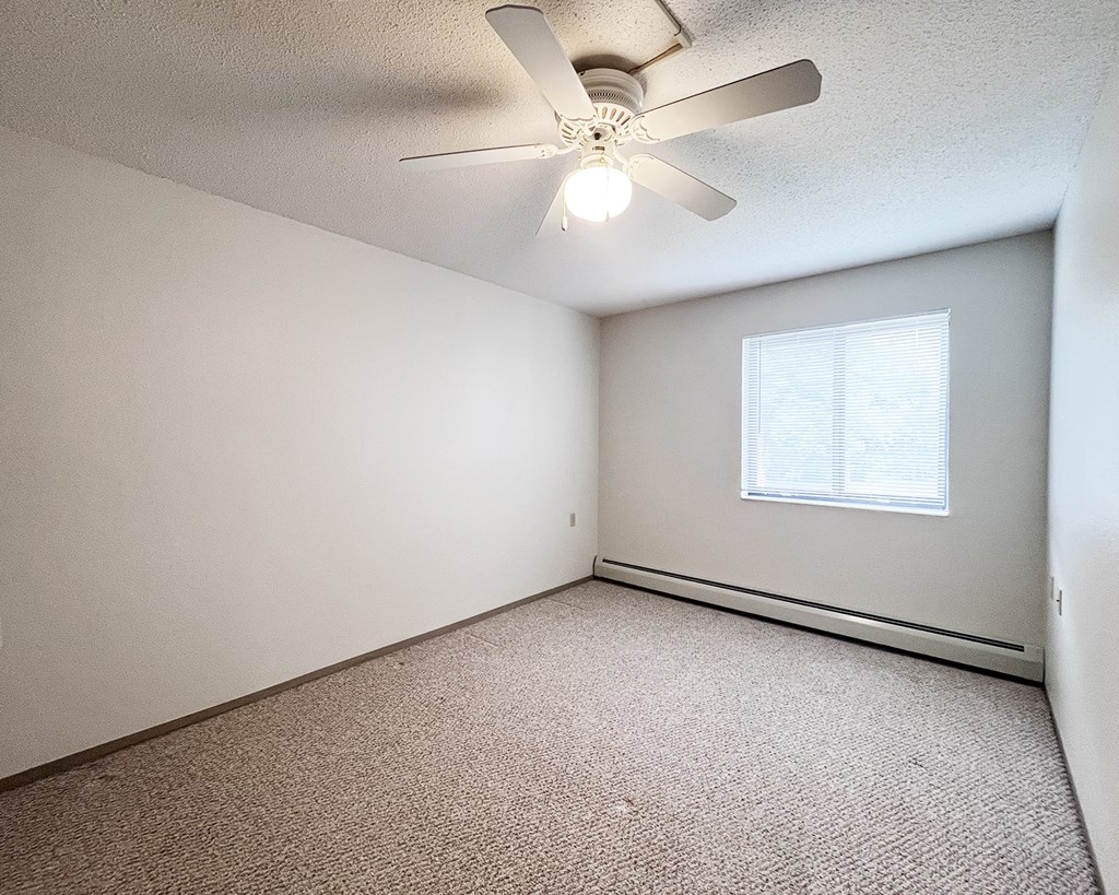A room with a ceiling fan and a window.