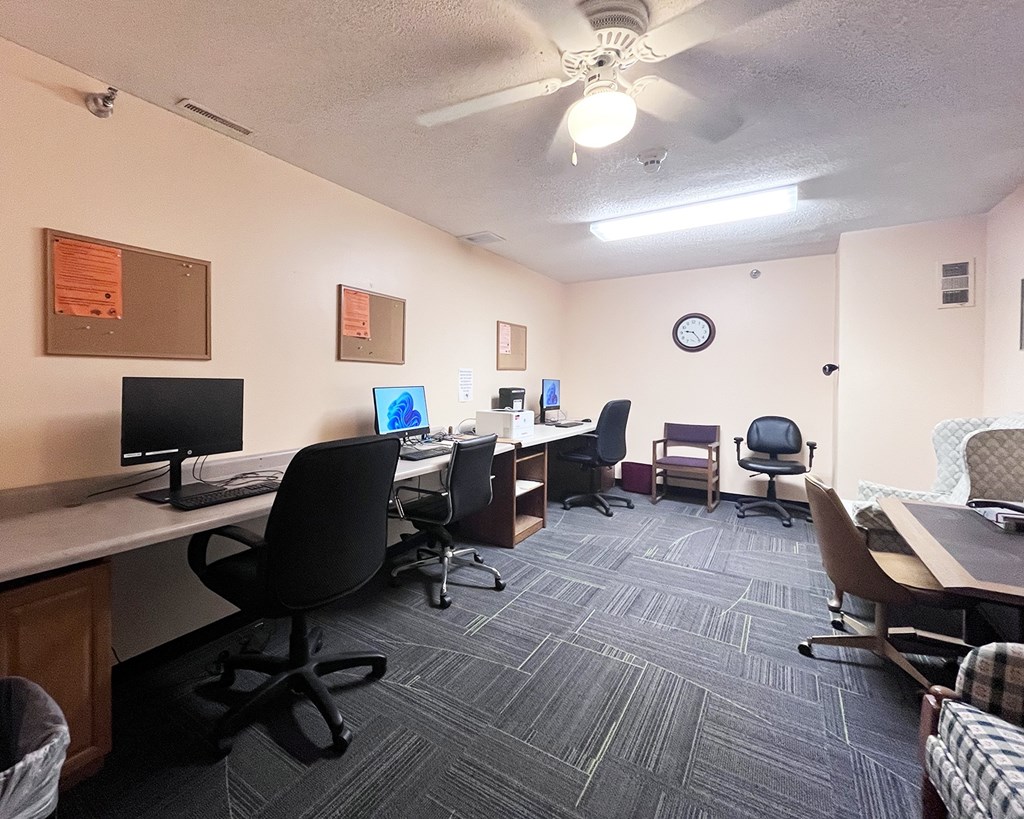 A room with a carpeted floor and a ceiling fan.
