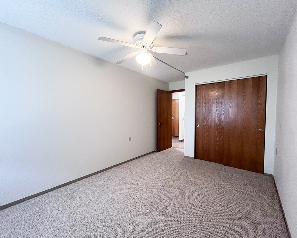 A room with a ceiling fan and carpeted floor.
