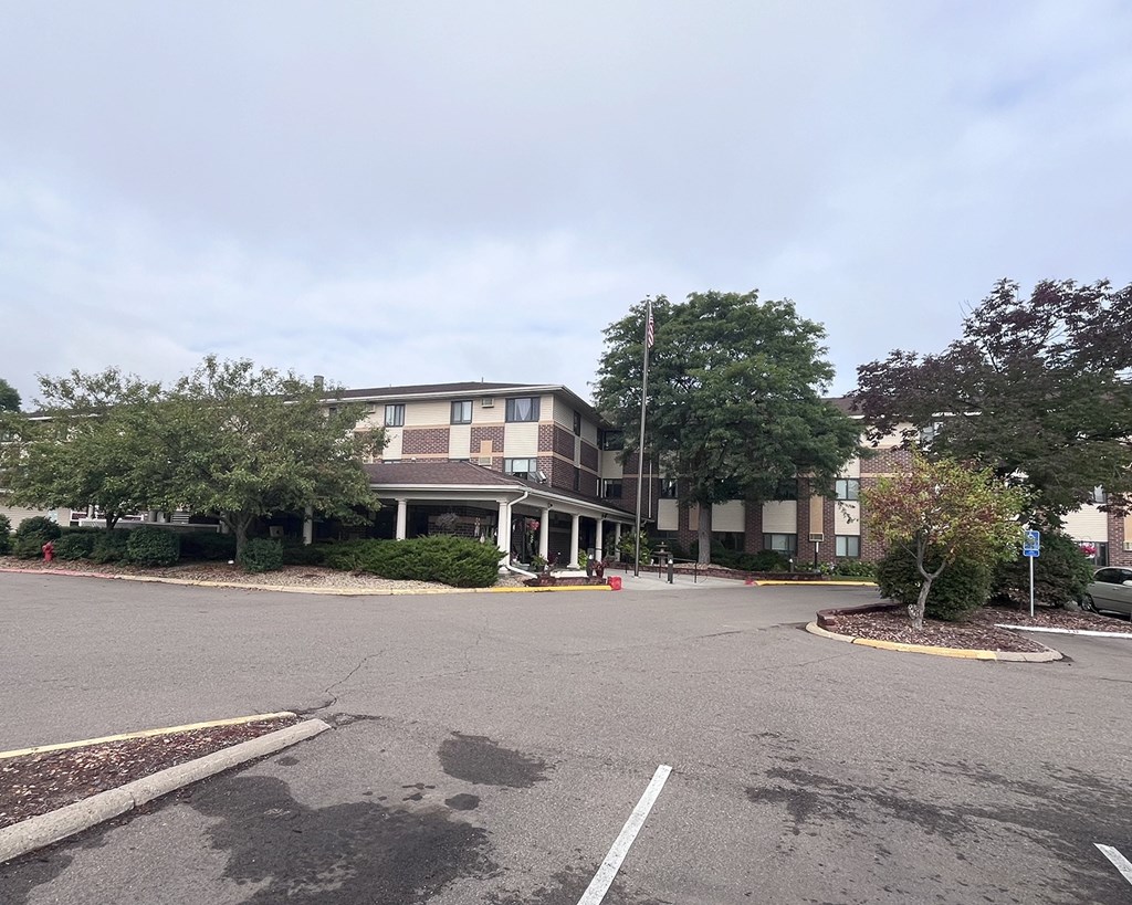 A parking lot in front of a building with a flag pole.