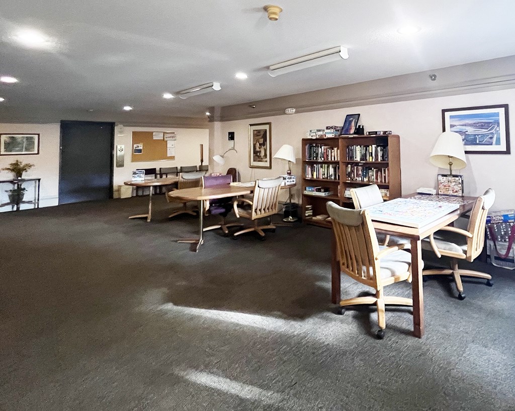 A room with a desk, chairs, and a bookshelf.