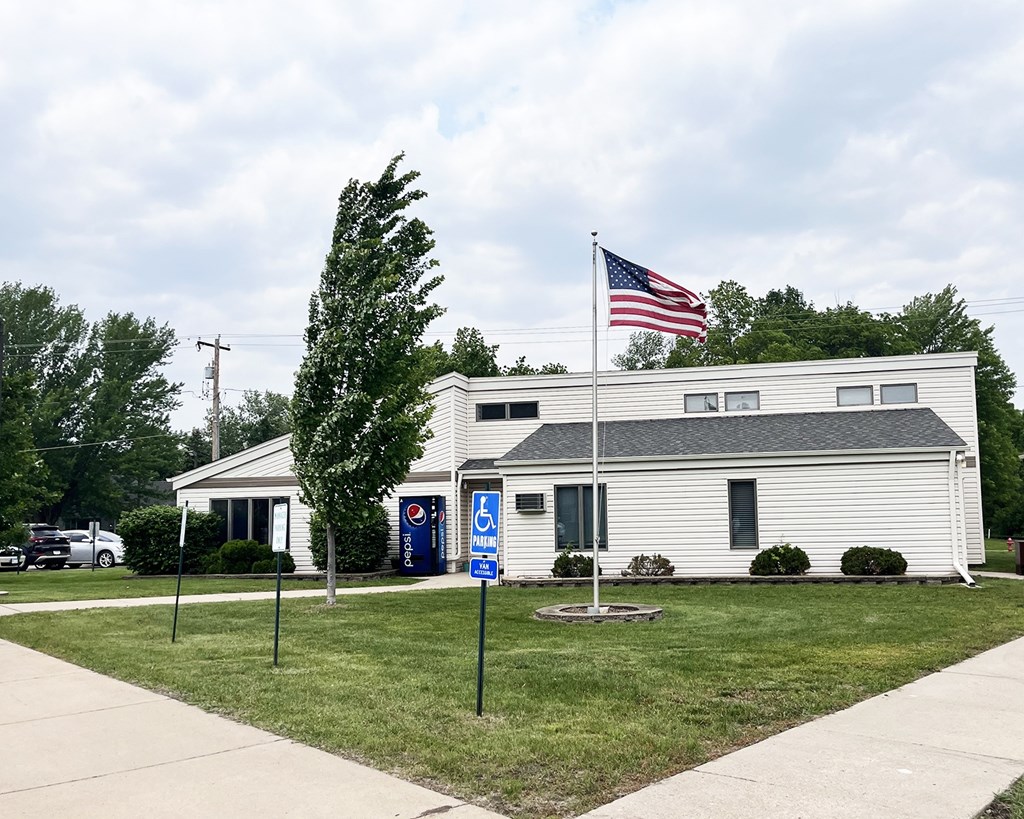 A white building with a Pepsi machine in front and an American flag on top.