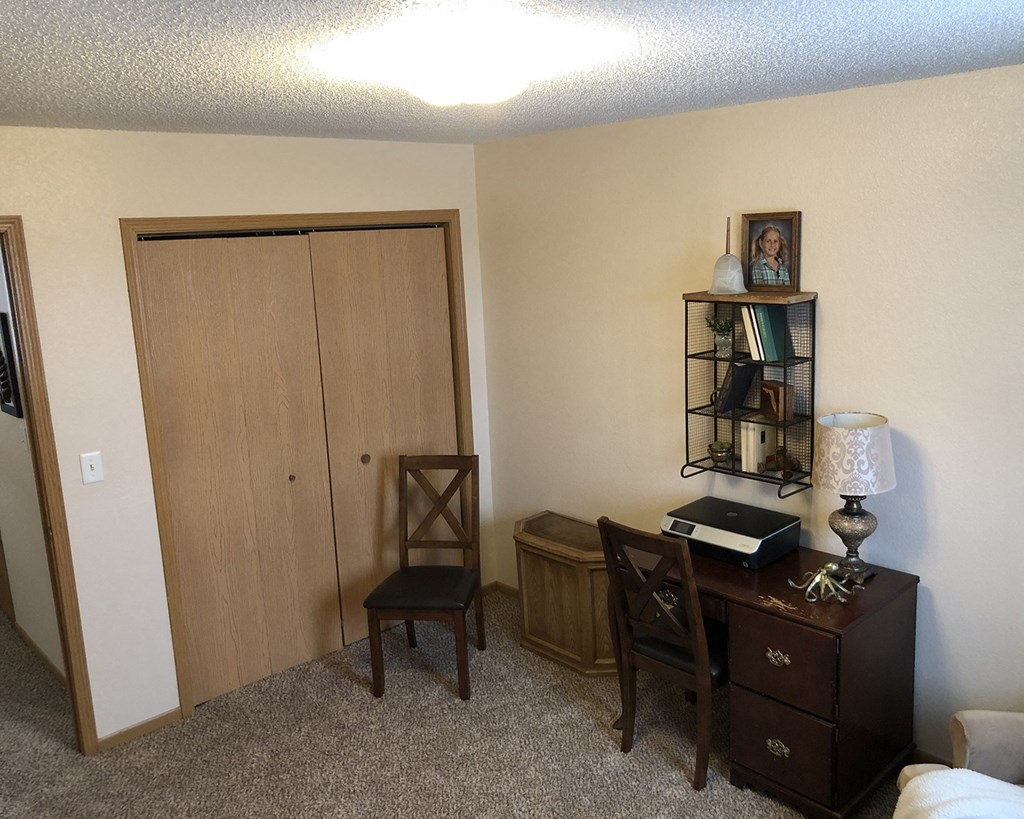 a bedroom with a desk and chair and a closet with a door