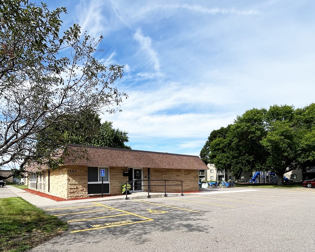A parking lot with a building and a tree in front.
