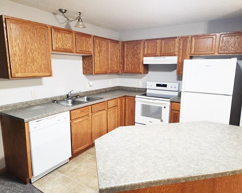 A kitchen with wooden cabinets and white appliances.