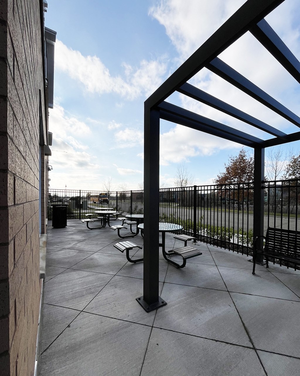 A patio with tables and chairs is covered by a roof.