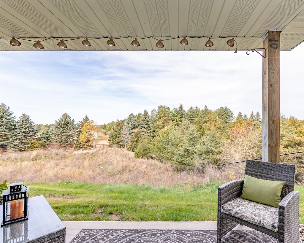 a porch with two chairs and a table overlooking a field and trees