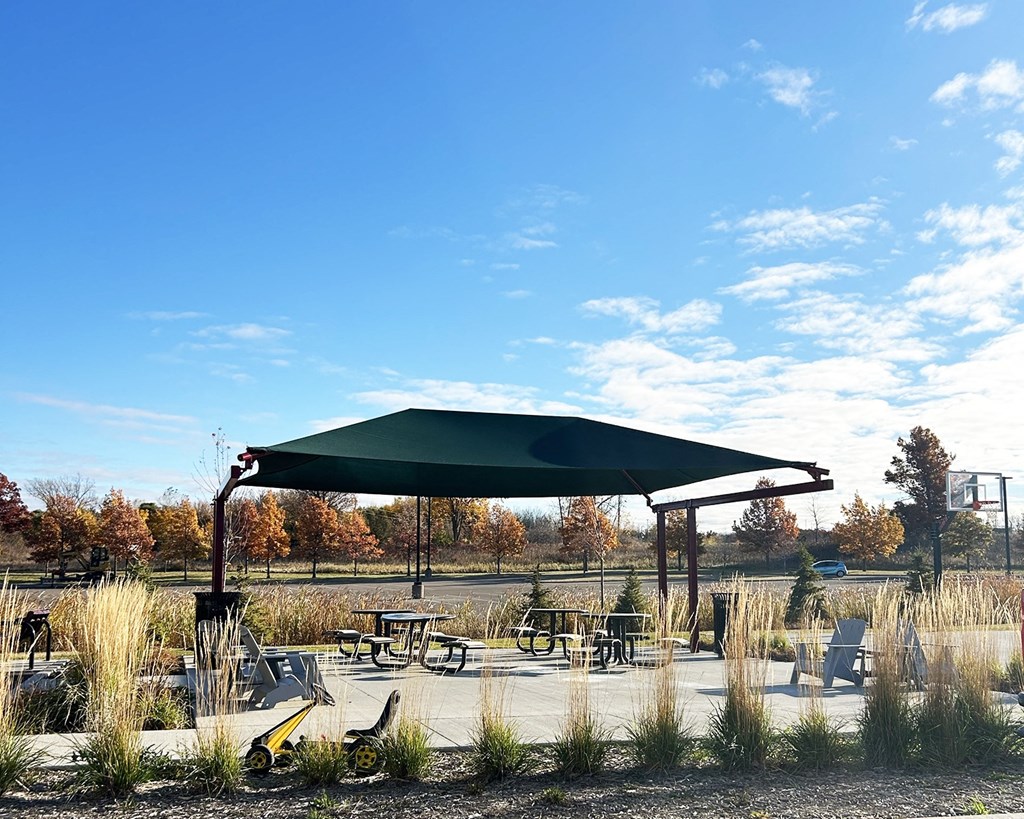 a patio with tables and chairs and a green canopy