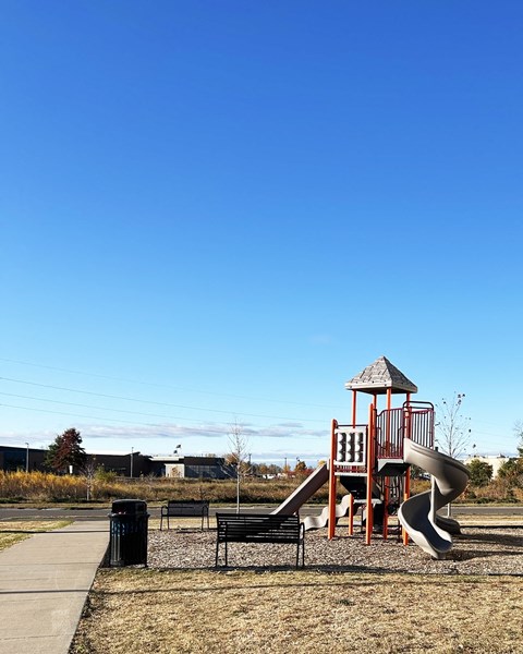 a playground with a slide and a bench in a park