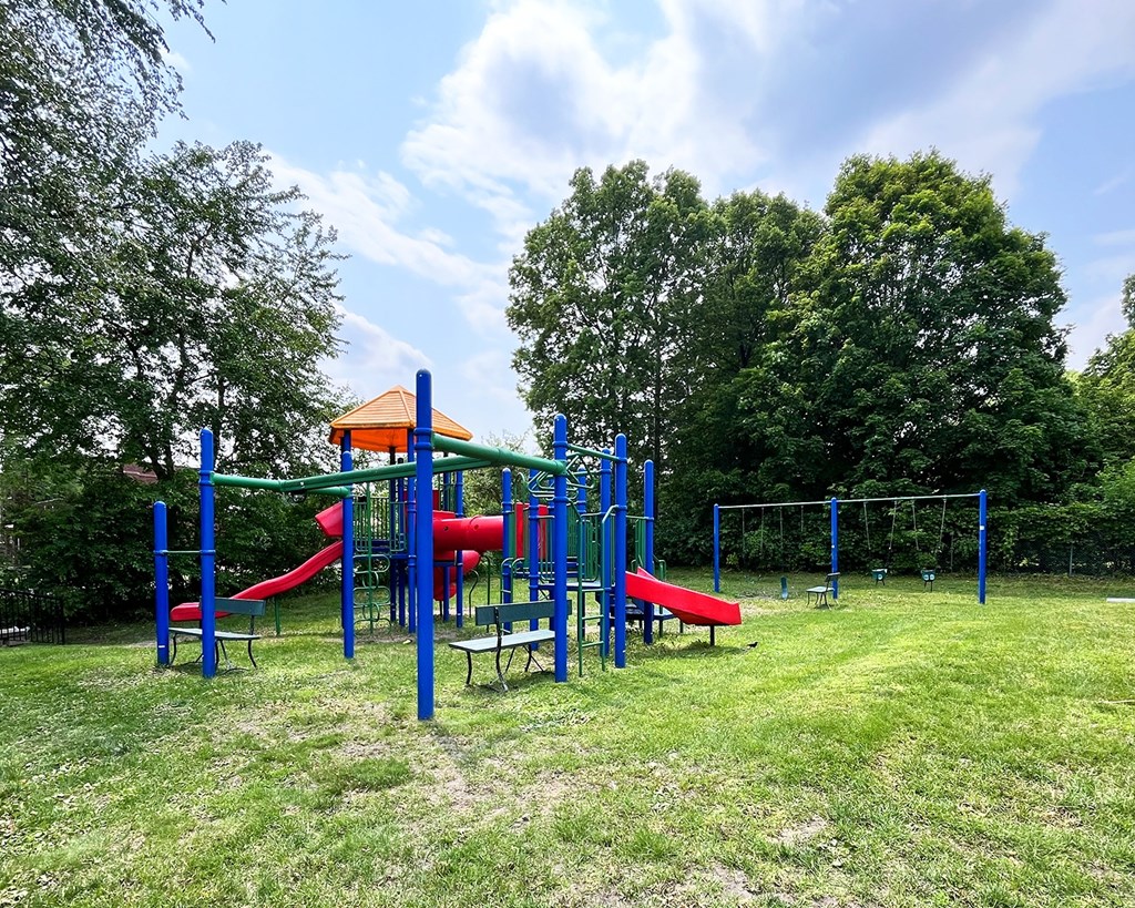 A playground with a red slide and blue poles.