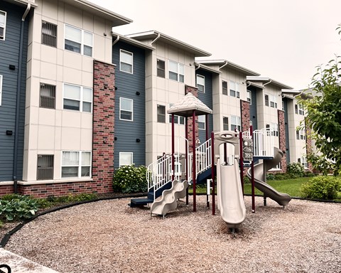 A playground with a slide in front of apartment buildings.
