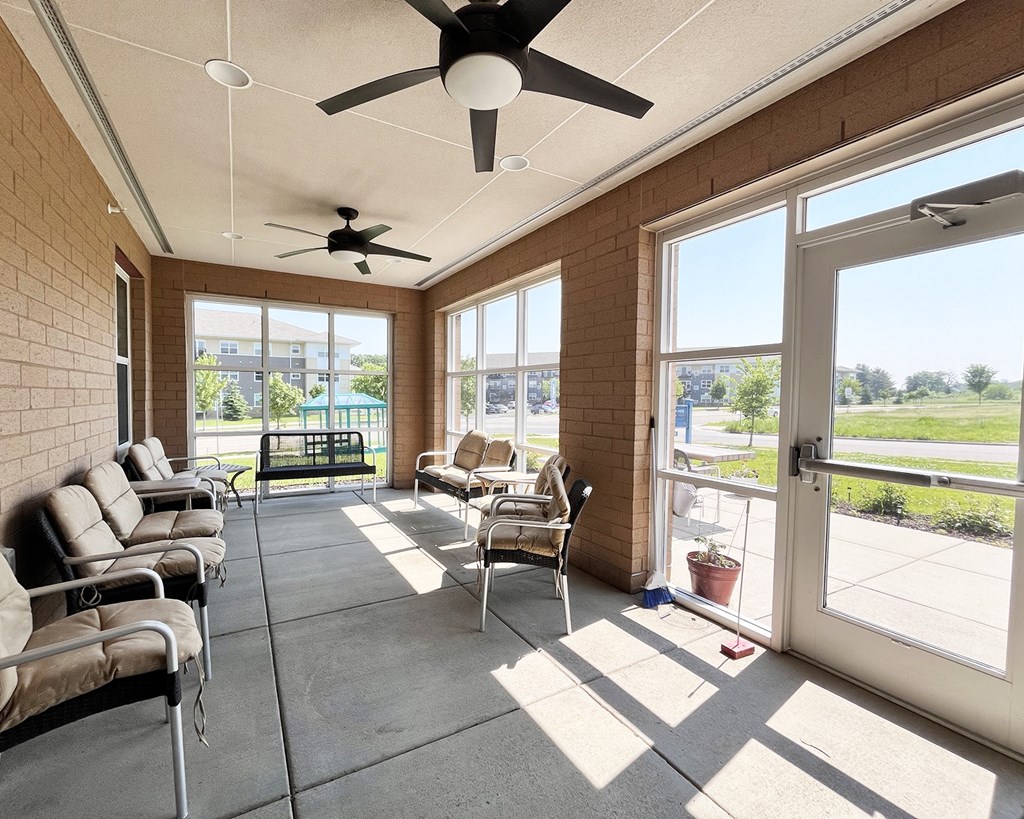 A sunny day in a room with a ceiling fan and a row of chairs.