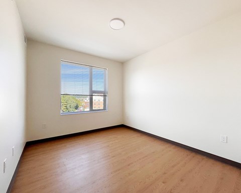 Empty room with a window and wooden floor.