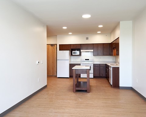 A kitchen with a white fridge and wooden floors.