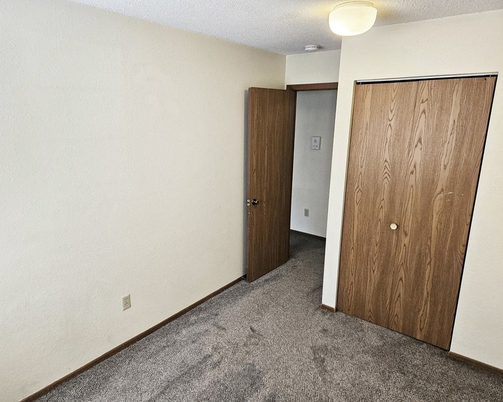 A room with two wooden doors and carpeted floor.
