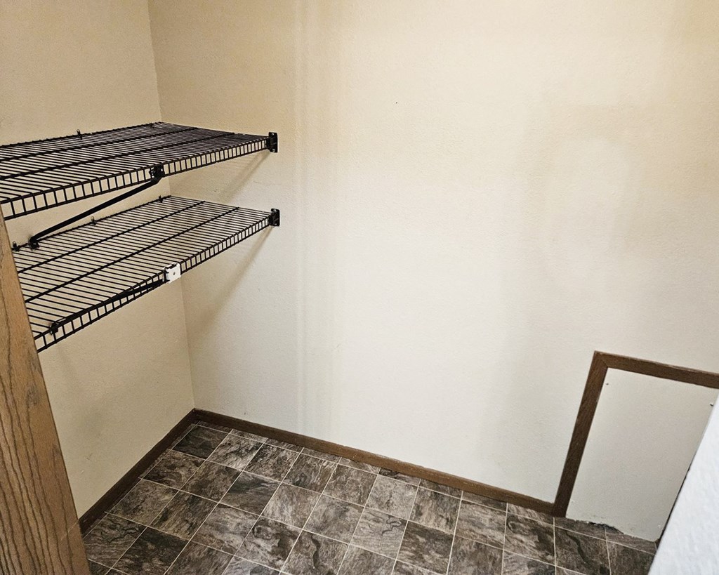 Empty shelves in a room with a mirror on the wall.