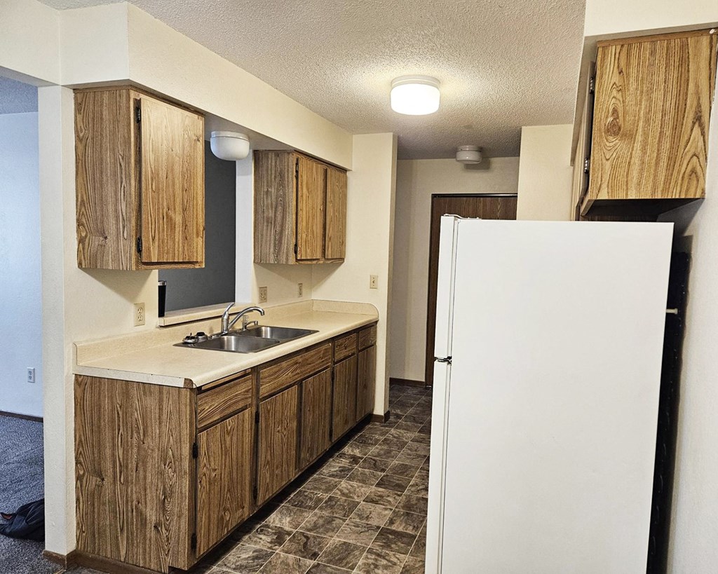 A kitchen with wooden cabinets and a white refrigerator.