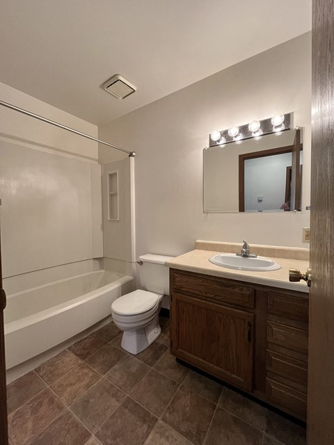 A bathroom with a toilet, sink, and mirror.