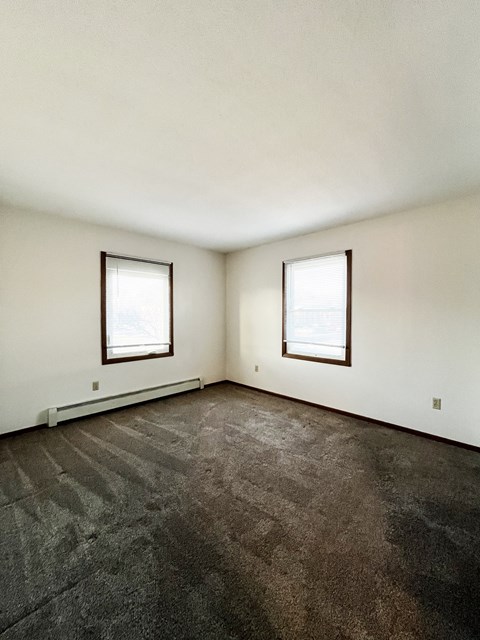 A room with two windows and a carpeted floor.