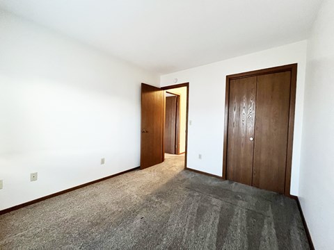 A room with a carpeted floor and two wooden doors.
