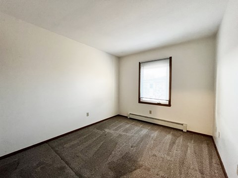 A room with a carpeted floor and a window.