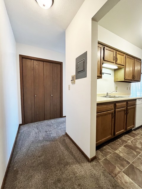 A kitchen with brown cabinets and a white wall.