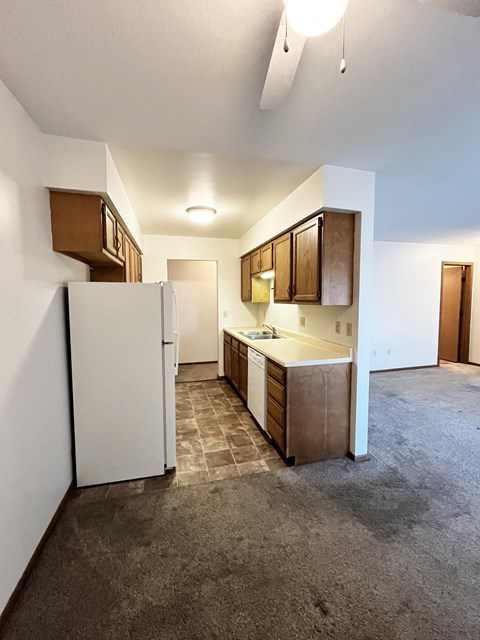 A kitchen with white appliances and wooden cabinets.