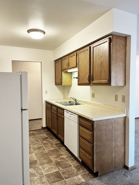 A kitchen with brown cabinets and a white refrigerator.