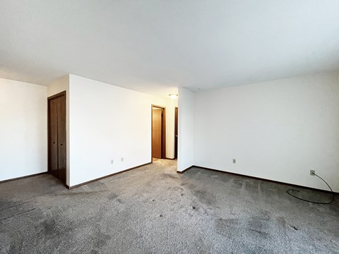 A room with a carpeted floor and two doors.