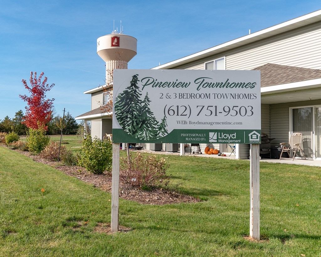 a sign in front of a house with a water tower