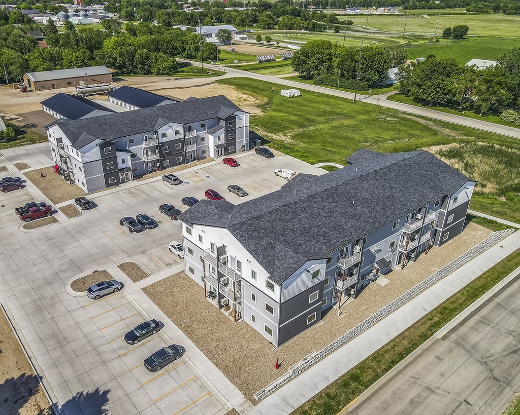 an aerial view of an apartment building with cars parked in a parking lot